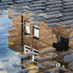 Cobblestone road with reflection of house in a puddle
